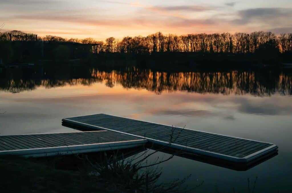 A tranquil dock situated on a still lake in the evening, at sunset