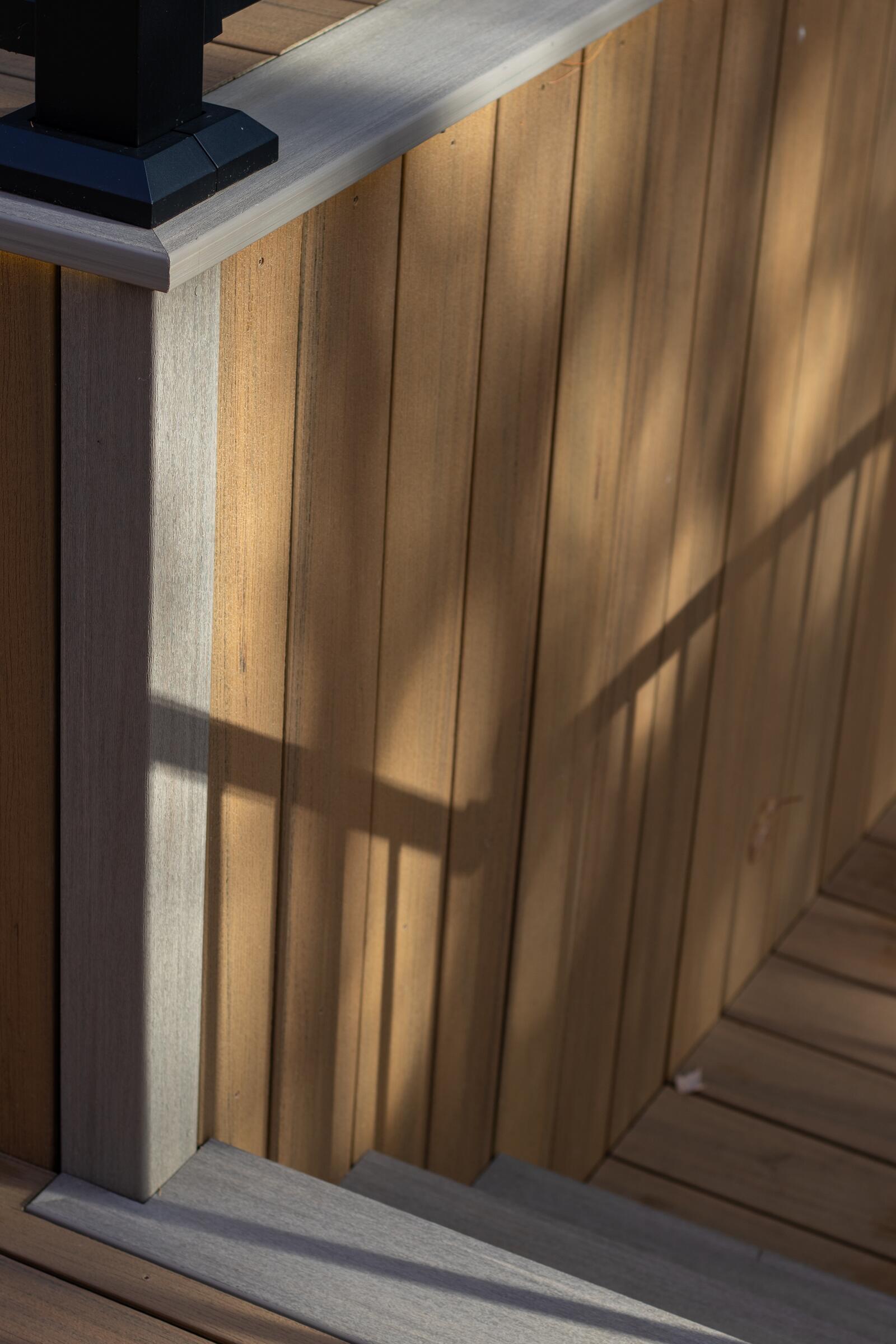 Close up of a cedar privacy wall and composite deck edge in warm light, Muskoka