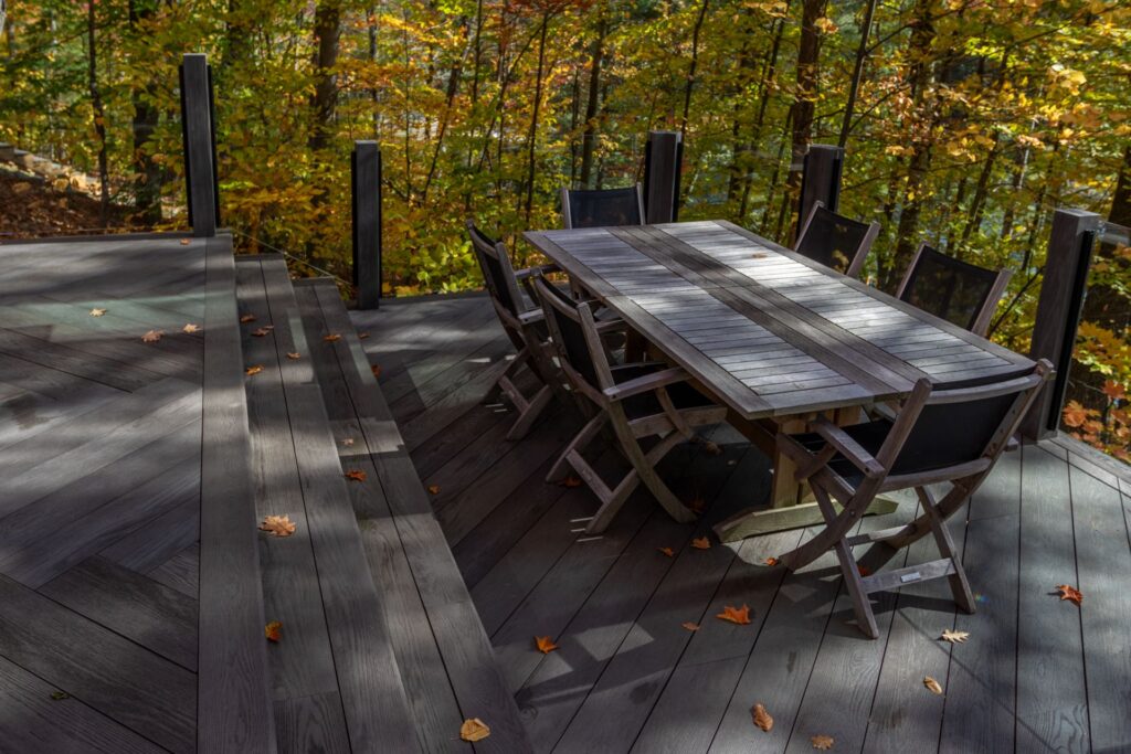 Composite deck with outdoor dining set surrounded by fall colours in Muskoka