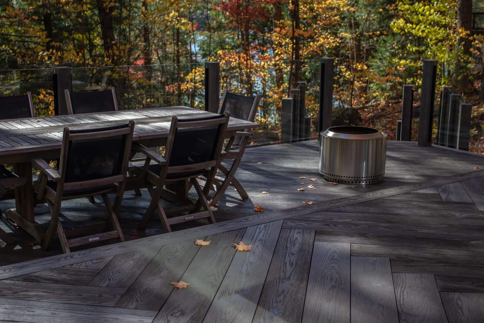 Herringbone composite deck with glass railing and fall colours in Muskoka