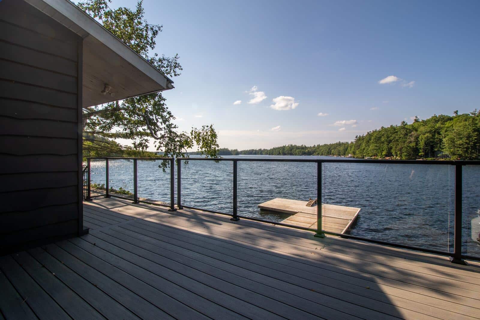Lakeside deck with cable railing looking out to a dock on open water in Muskoka