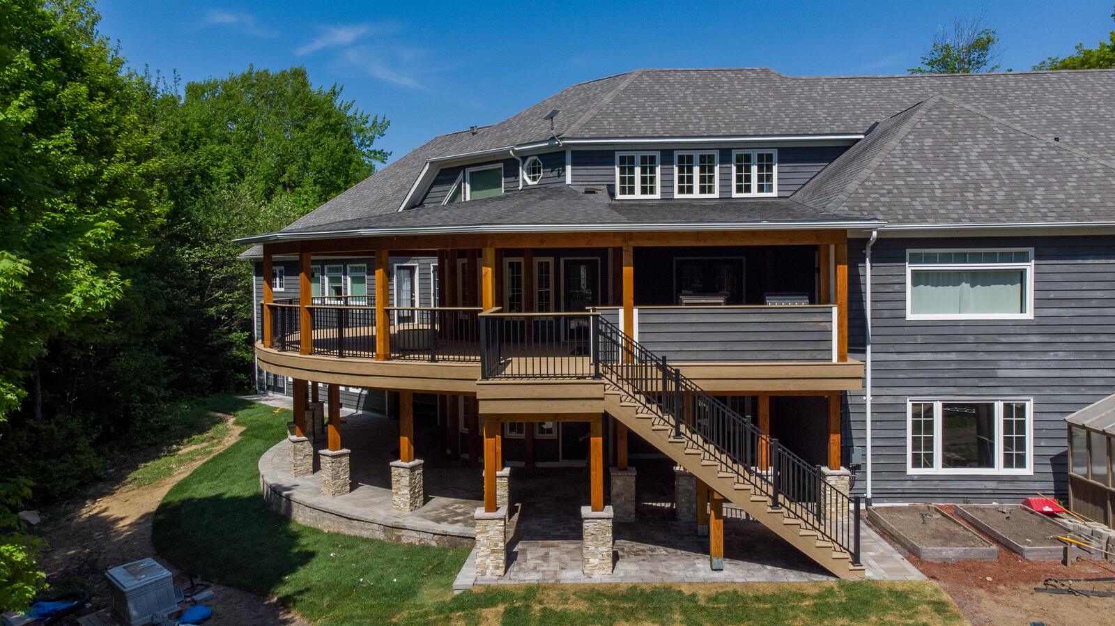 Large waterfront home with a curved covered deck and stone piers in Muskoka