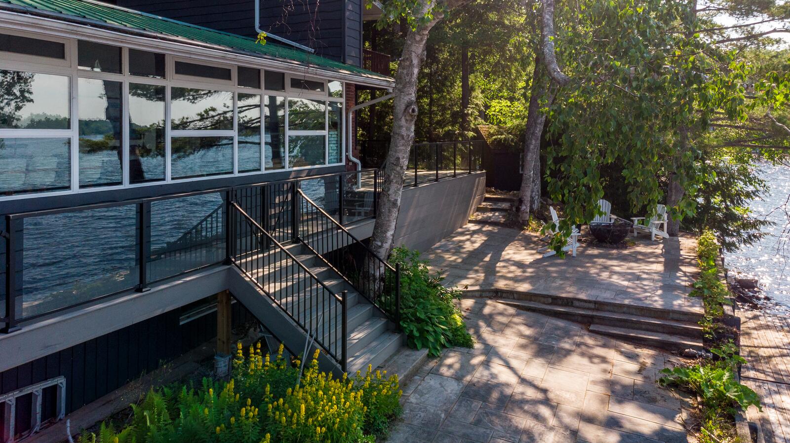 Waterfront home with a custom deck, stairs and stone patio in Muskoka