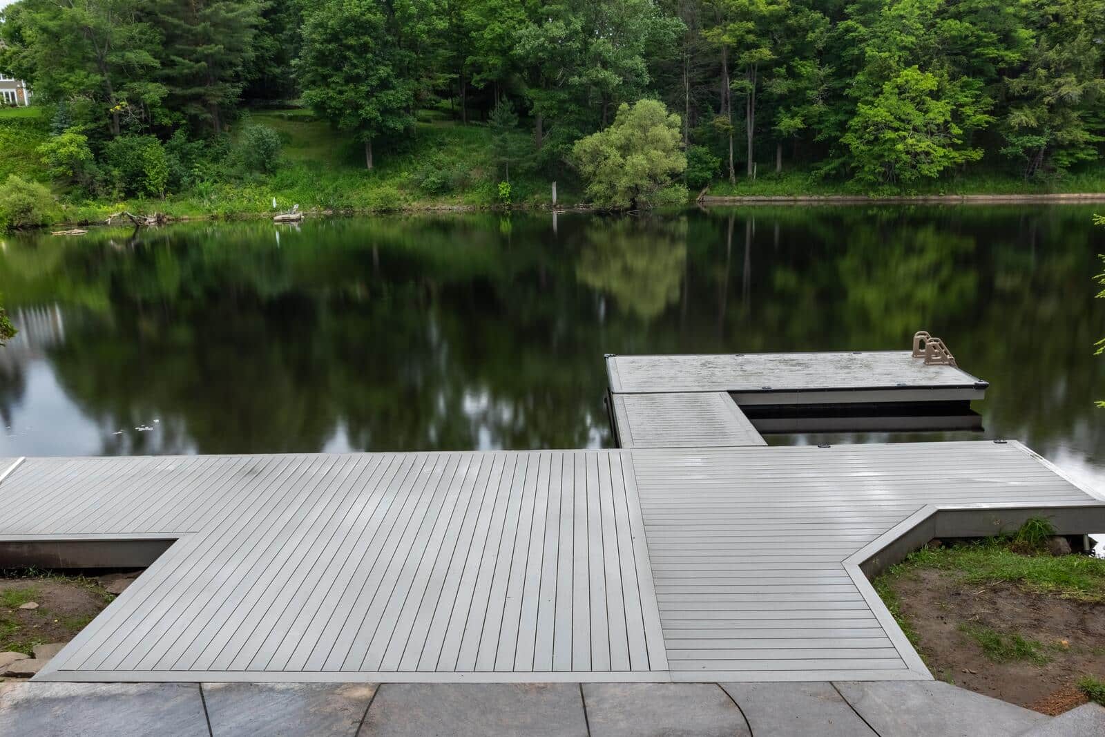 Wide composite dock on a still, forested shoreline in Muskoka